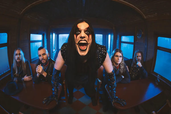 Swedish metal band Avatar wearing makeup and theatrical attire while posing inside a train car for a wide-angle promo photo.