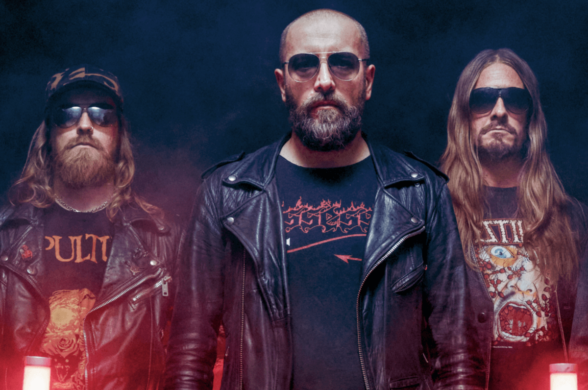 Promotional portrait of Swedish death metal band Bloodbath posing in leather jackets under moody red and blue lighting.