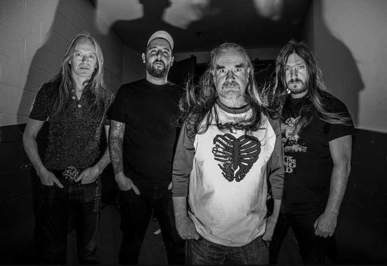 British extreme metal band Carcass standing in a hallway for a black-and-white promotional photo.