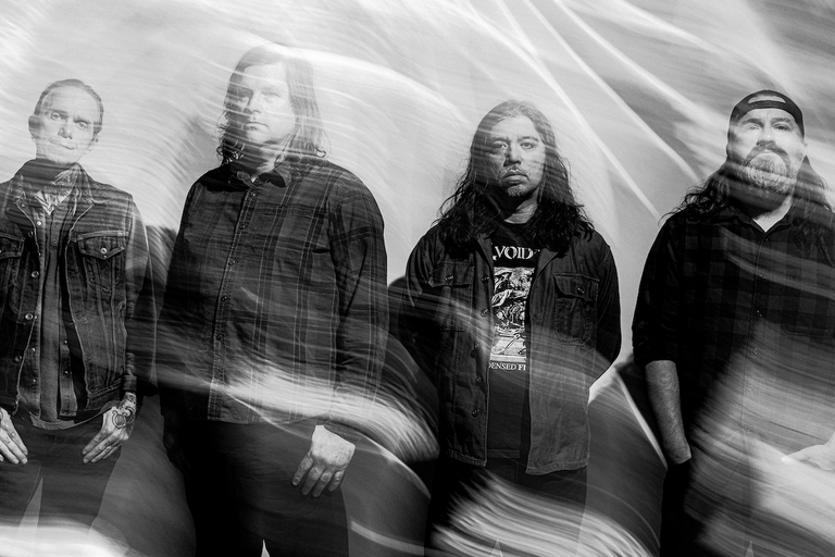 Black and white promo photo of American hardcore punk band Converge members standing together with smoky, motion-blurred light streaks overlaying them.