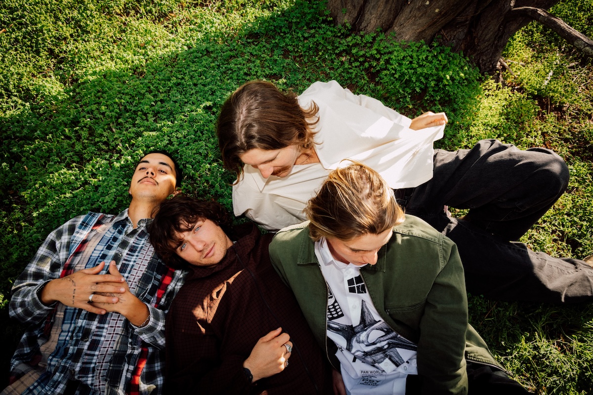 Australian indie rock band DICE laying together in the grass beneath a tree during an outdoor promo photo shoot.