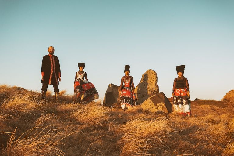 Ukrainian folk group DakhaBrakha posing outdoors in traditional attire and tall fur hats.