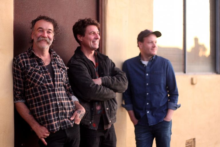 Australian rock band Epicure members leaning casually against a building exterior wall during a photoshoot.