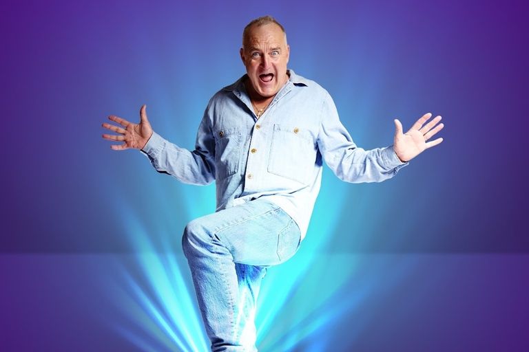 Comedian Jimeoin posing dynamically with arms wide and one leg raised against a blue and purple gradient background with blue light rays.