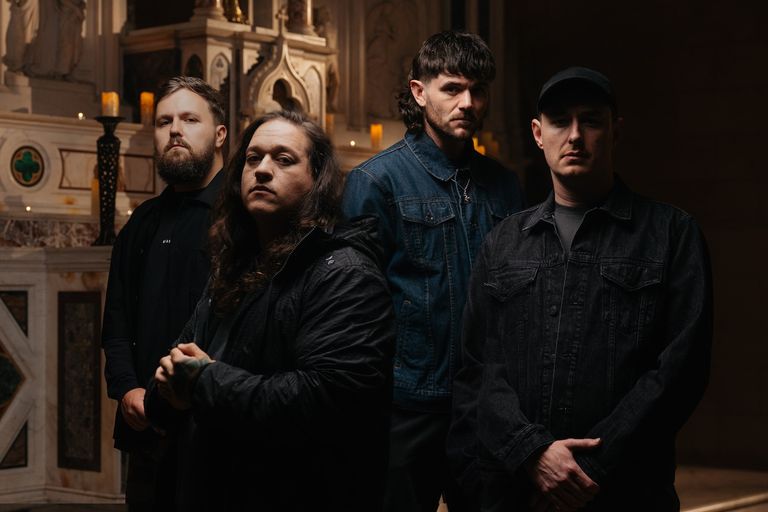 Promotional portrait of Australian metalcore band Polaris standing together inside a dimly lit church or cathedral setting.