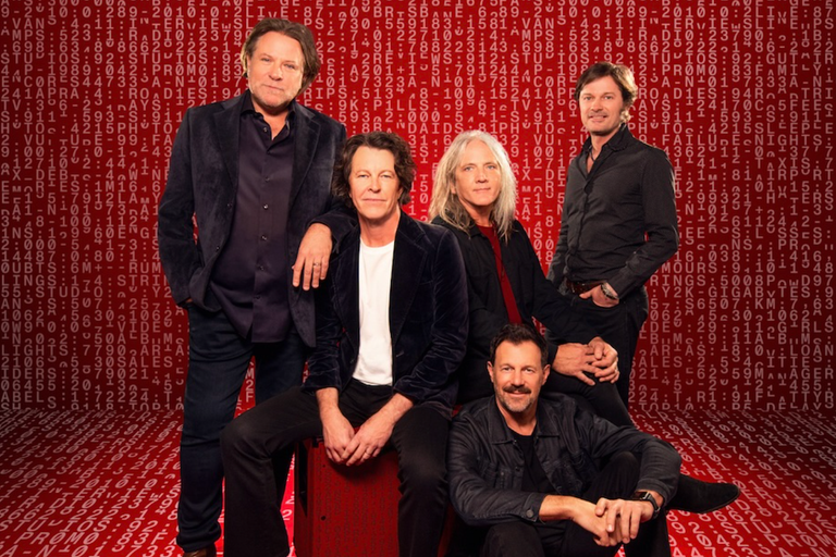 Australian rock band Powderfinger members pose together in dark outfits against a red backdrop filled with repeating digital numbers and letters.