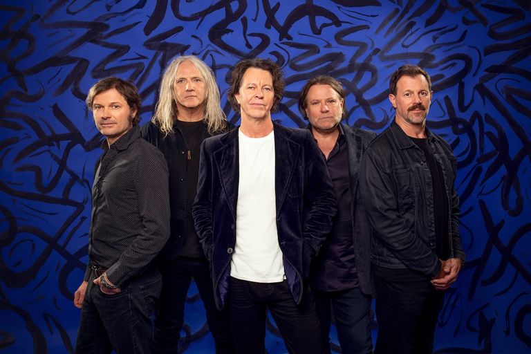 Promotional portrait of Australian rock band Powderfinger posing in dark jackets against a stylized blue background.
