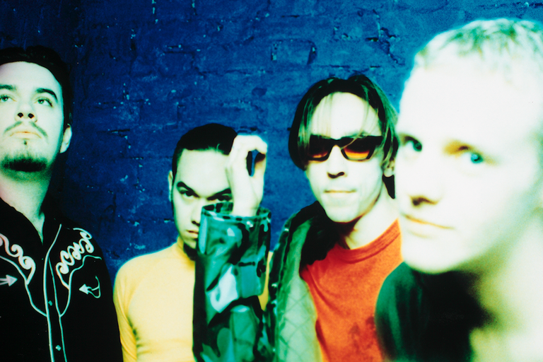 Promotional photo of New Zealand rock band Shihad posing against a textured blue wall background.