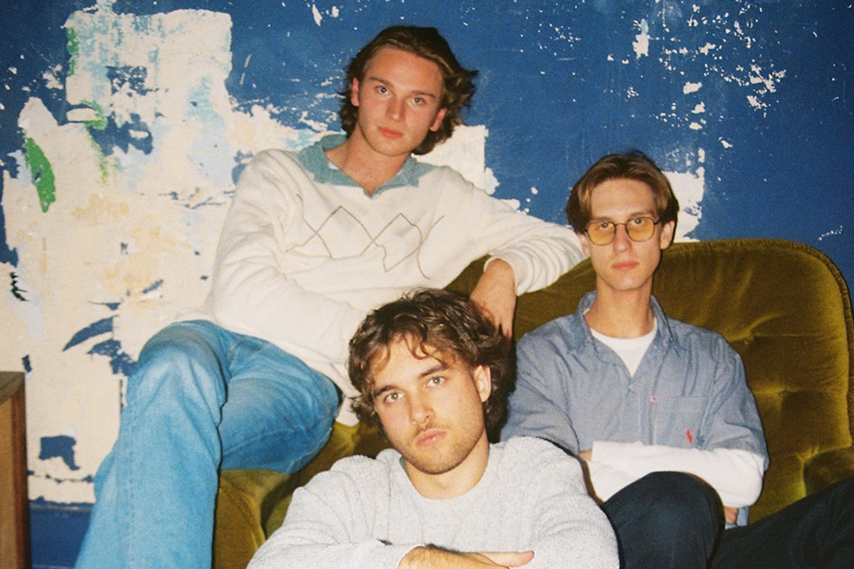 Australian indie band TOWNHOUSE members posing together indoors on a vintage green velvet couch against a blue distressed wall.