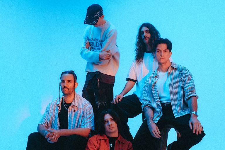 Australian metalcore band Windwaker poses together in casual street style clothing against a vibrant blue studio backdrop.
