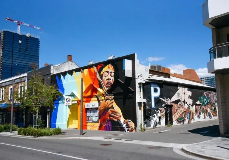 Exterior of live music venue Jive in Adelaide, showcasing a vibrant outdoor wall mural of Jimi Hendrix under a clear blue sky.